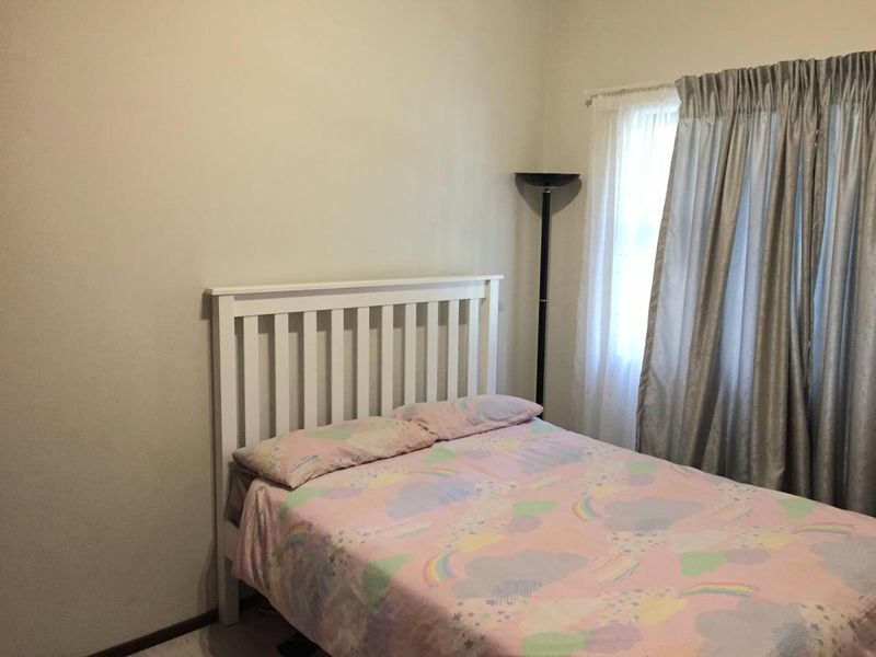 A standard bedroom featuring neutral wall finishes and a window with curtain tracks.