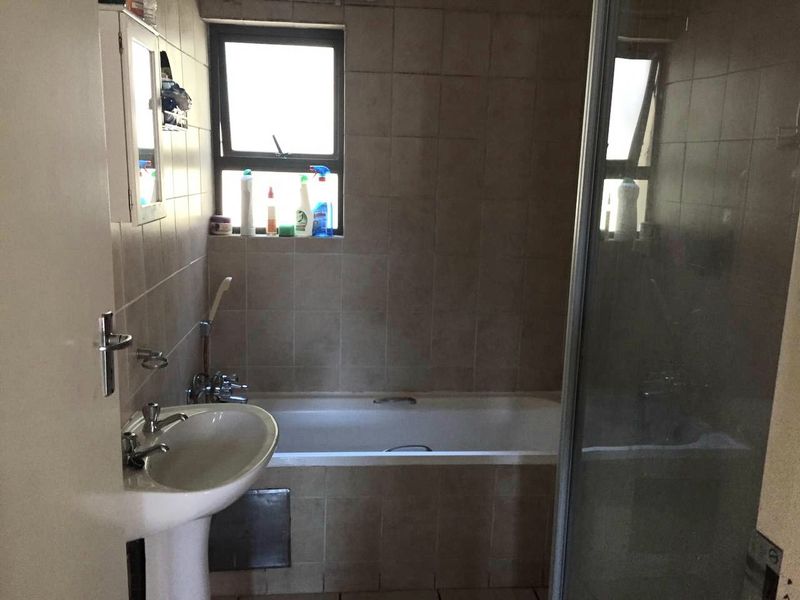 A dated bathroom featuring a pedestal basin, bathtub, and separate shower enclosure with tiled finishes throughout.