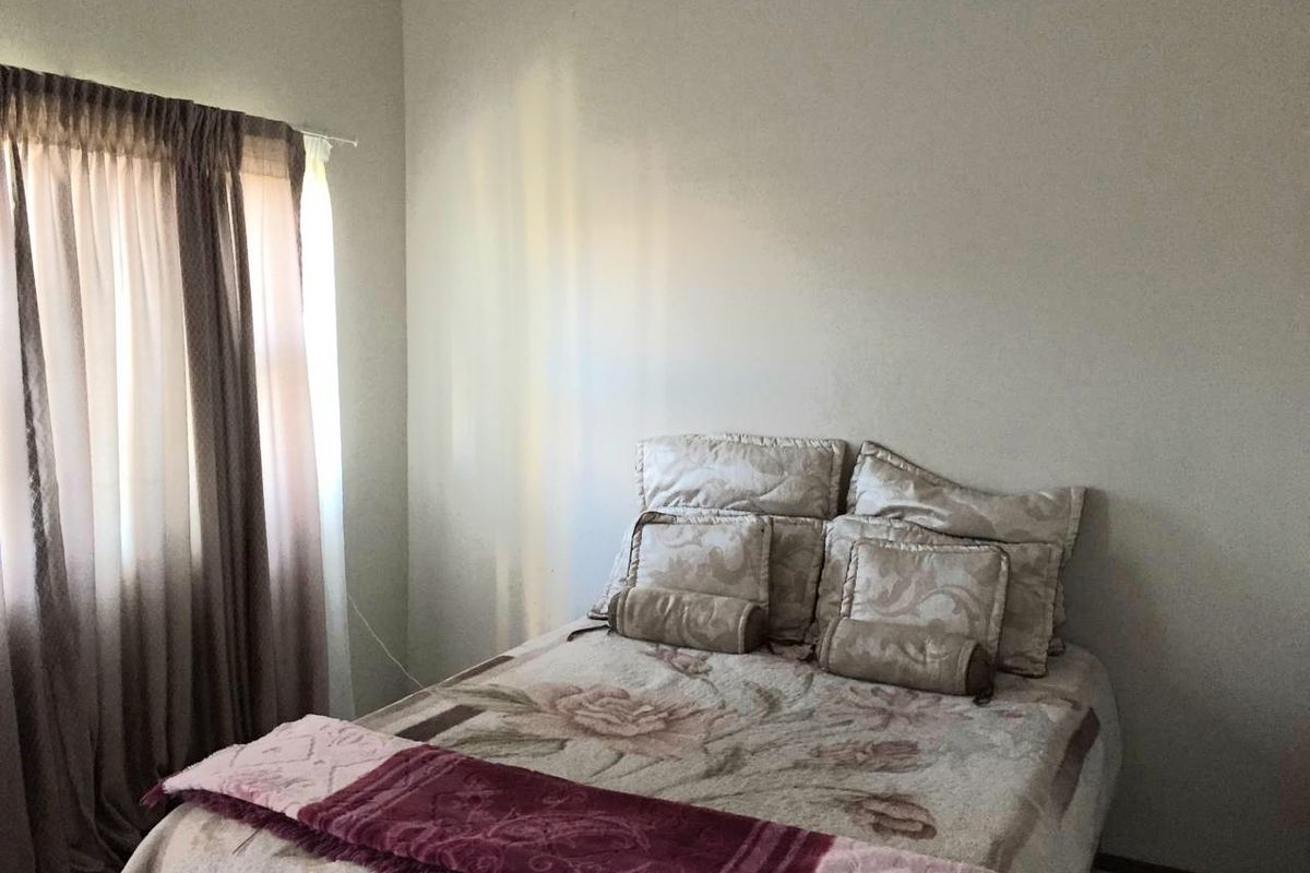 A standard bedroom featuring neutral wall finishes and a window with curtain tracks.