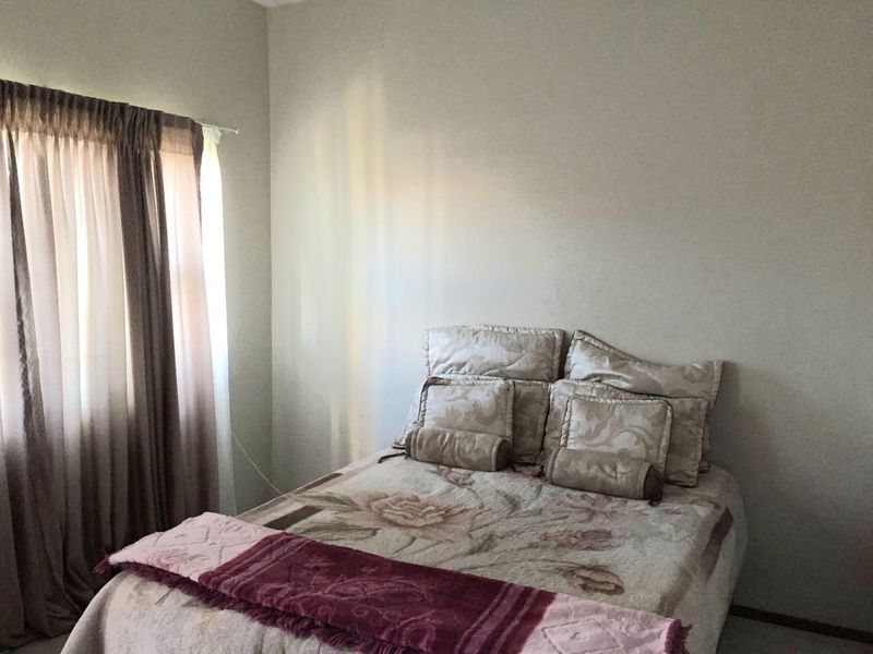 A standard bedroom featuring neutral wall finishes and a window with curtain tracks.