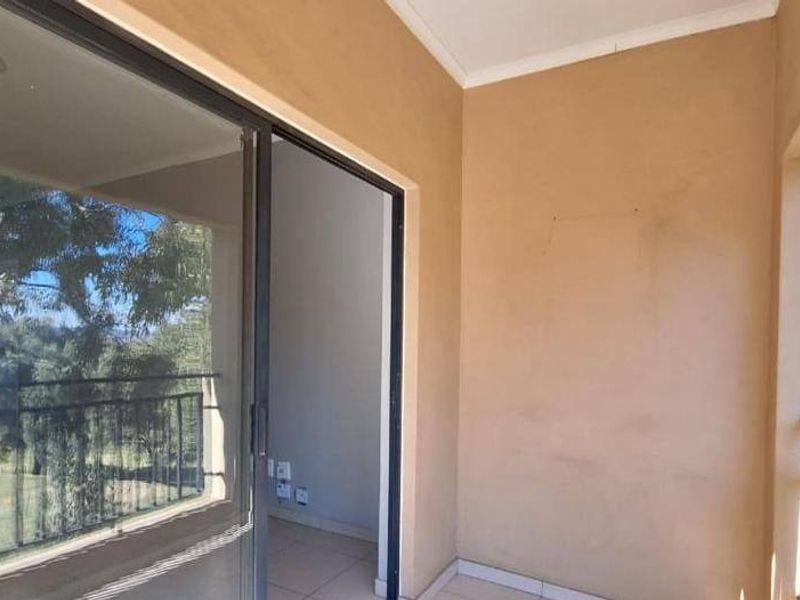 A covered balcony featuring tiled flooring, a metal balustrade, and a sliding glass door providing access to the interior living space.