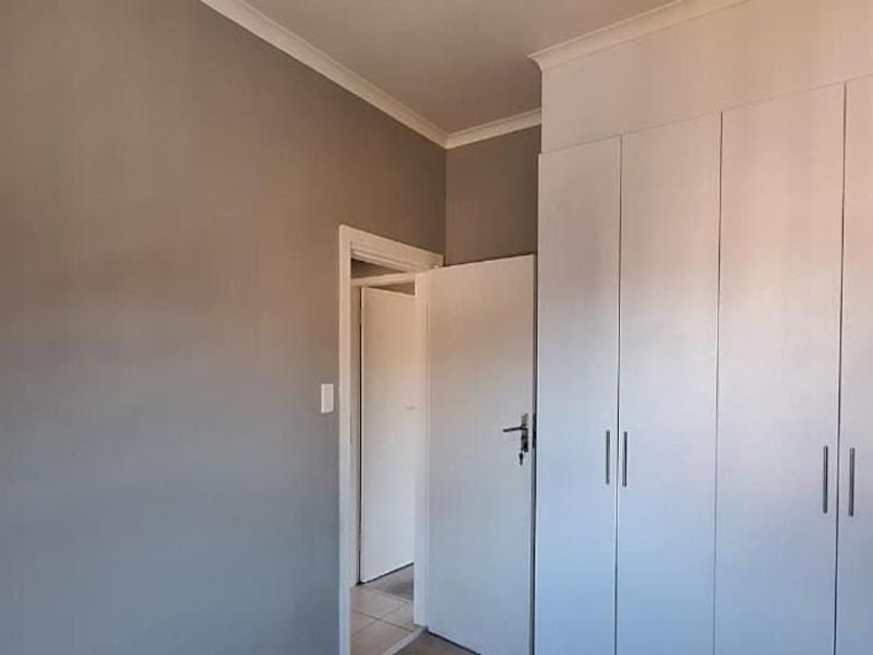 A clean, neutral bedroom featuring built-in cupboards and coving, offering a blank canvas for personalization.