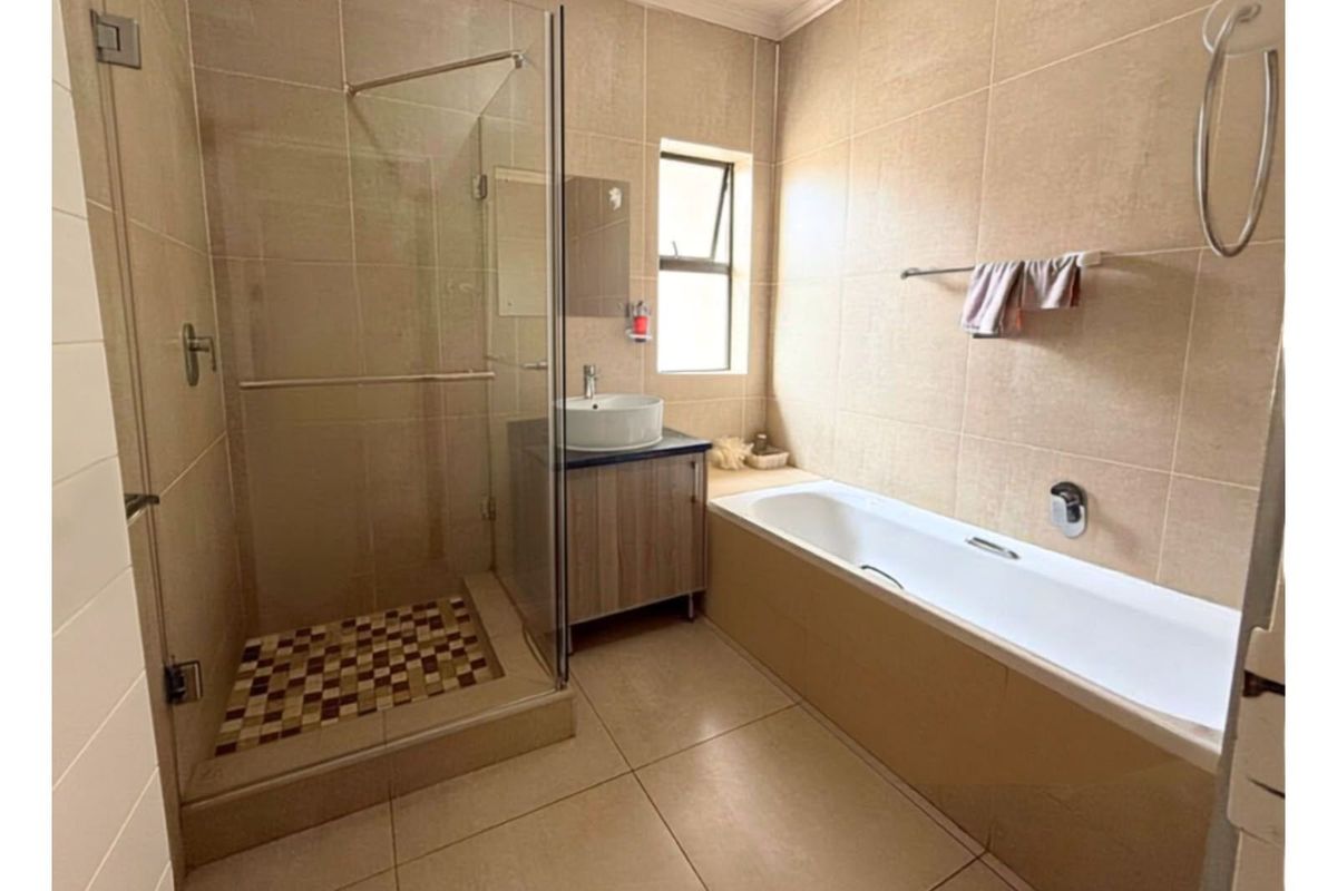 A well-maintained bathroom featuring a glass-enclosed shower, a built-in bathtub, and a modern vanity with a vessel sink.