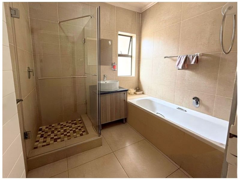 A well-maintained bathroom featuring a glass-enclosed shower, a built-in bathtub, and a modern vanity with a vessel sink.