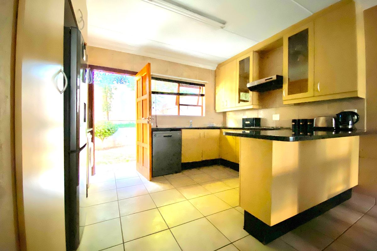 A functional kitchen featuring built-in cabinetry, granite countertops, and tiled flooring, with direct access to the exterior through a side door.
