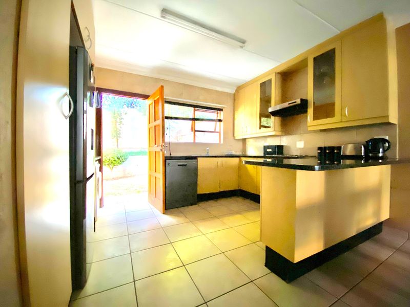 A functional kitchen featuring built-in cabinetry, granite countertops, and tiled flooring, with direct access to the exterior through a side door.