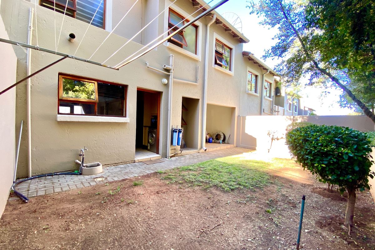 Rear exterior view of the cluster property featuring a small garden, paved walkway, external water filtration system, and washing line.