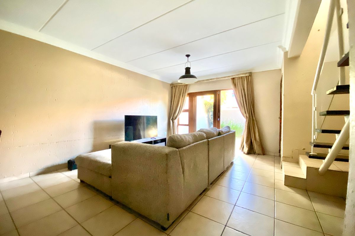 A living room featuring tiled flooring, a staircase, and a sliding glass door providing access to the exterior.