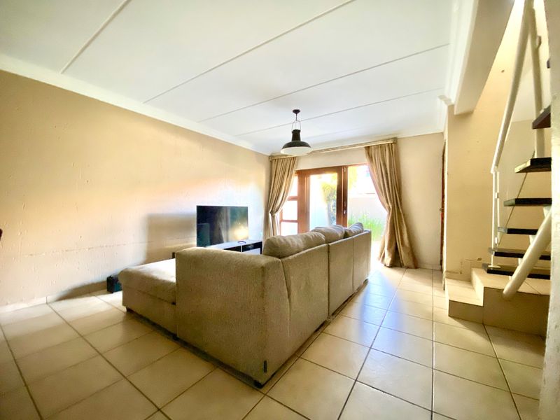 A living room featuring tiled flooring, a staircase, and a sliding glass door providing access to the exterior.
