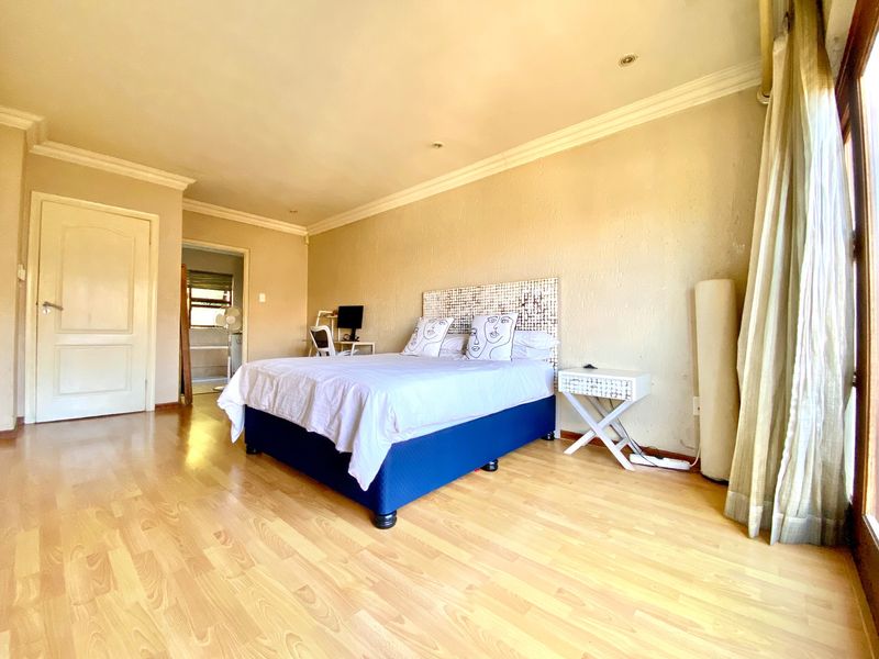 Spacious bedroom featuring laminate flooring, recessed downlighting, and direct access to an outdoor area via sliding doors.