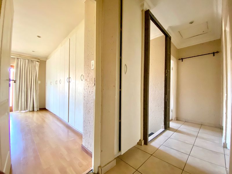 A functional hallway featuring built-in cupboards, a mix of laminate and tiled flooring, and recessed ceiling lighting, providing ample storage and transition space.