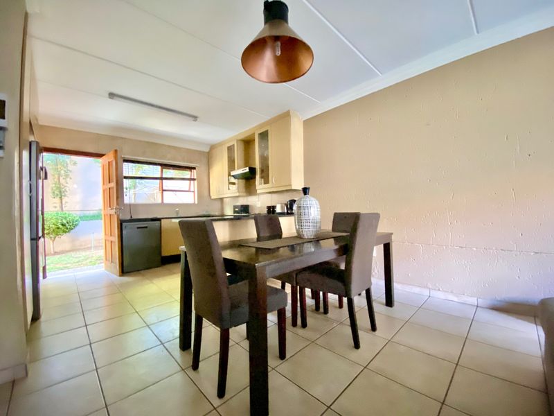 Open-plan kitchen and dining area featuring tiled flooring, built-in cabinetry, and direct access to the exterior.