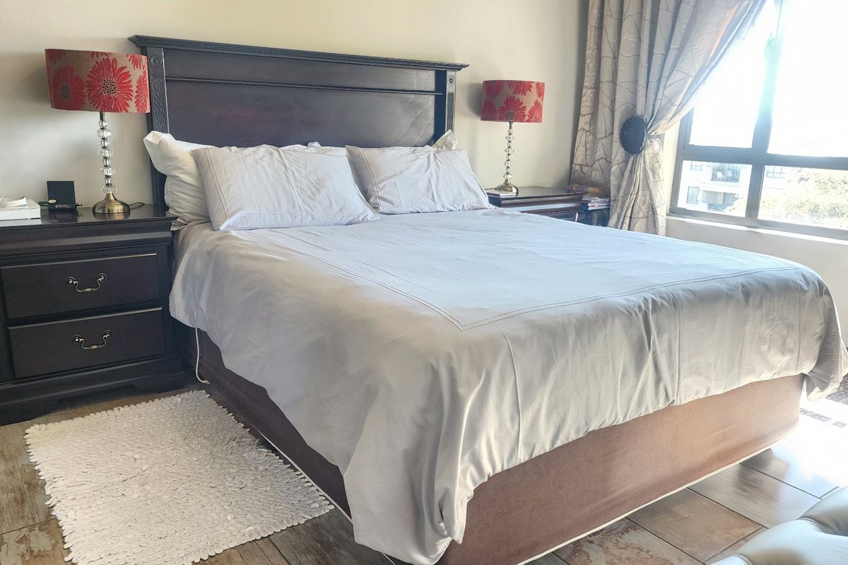 A well-lit bedroom featuring tiled flooring and a large window, providing a comfortable and functional living space.