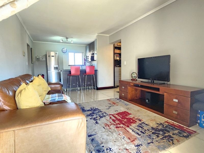Open plan living area featuring tiled flooring, a kitchen island with breakfast bar seating, and a separate pantry area.