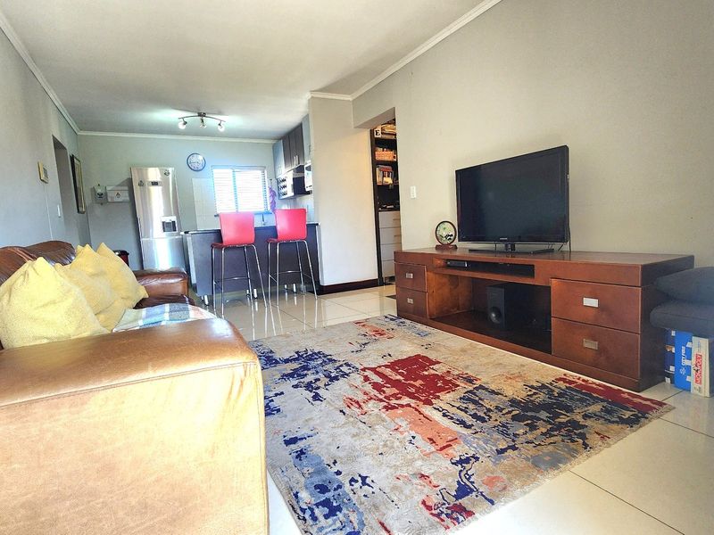 Open-plan living area featuring tiled flooring and a connected kitchen space with a breakfast island.