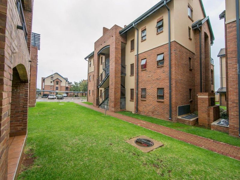 Exterior view of a multi-story apartment complex featuring face brick architecture, paved walkways, and well-maintained communal lawn areas.