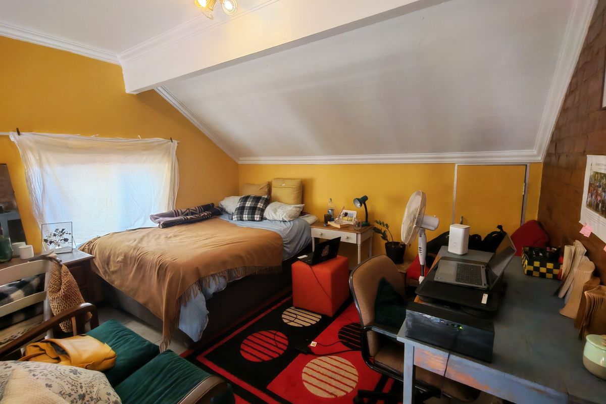A bedroom featuring a sloped ceiling with crown molding and an exposed brick wall, offering a unique architectural layout.