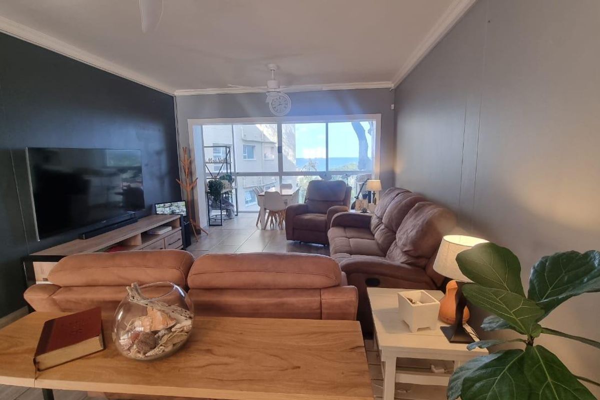Spacious living room featuring tiled flooring, a ceiling fan, and large sliding glass doors that provide natural light and access to the balcony.