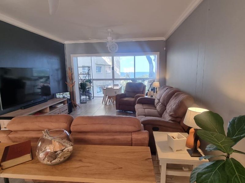 Spacious living room featuring tiled flooring, a ceiling fan, and large sliding glass doors that provide natural light and access to the balcony.