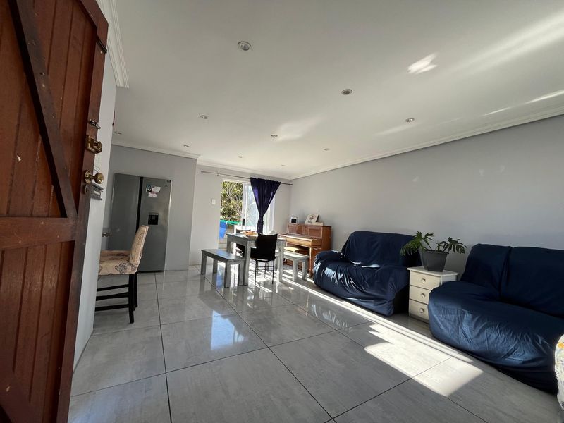 Spacious open-plan living area featuring large format floor tiles, recessed downlighting, and direct access to the outdoor area through a sliding glass door.