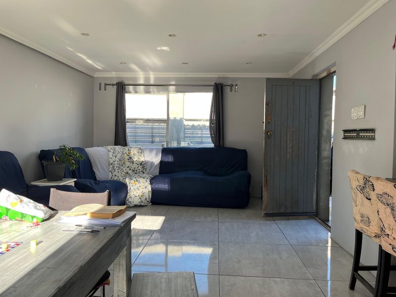 A living room featuring tiled flooring, recessed downlighting, and direct access to an exterior entrance.