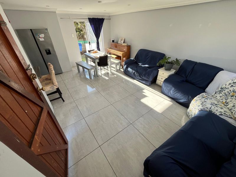 Open-plan living and dining area featuring large format floor tiles, recessed lighting, and direct access to the outdoor space through a sliding glass door.