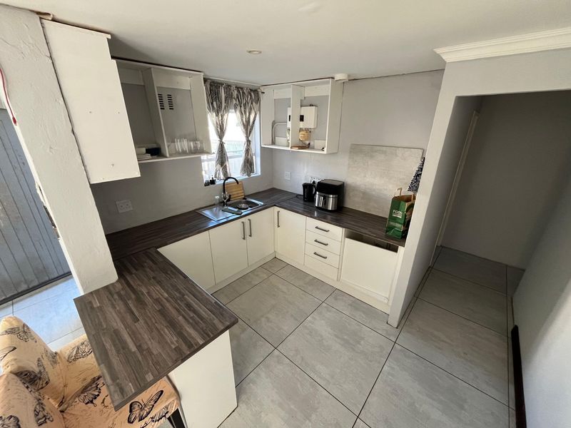 Compact kitchen featuring laminate countertops, tiled flooring, and built-in cabinetry, currently requiring minor finishing touches and cabinet door replacements.
