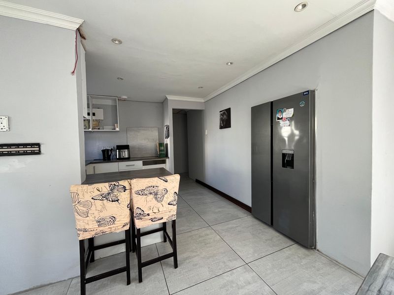 A functional kitchen area featuring tiled flooring, recessed lighting, and a breakfast counter, requiring minor finishing touches to the walls and electrical fixtures.