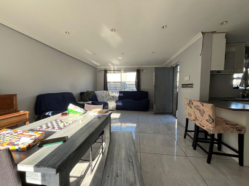 Open plan living and kitchen area featuring tiled flooring, recessed lighting, and a breakfast bar, offering a versatile space for daily living.