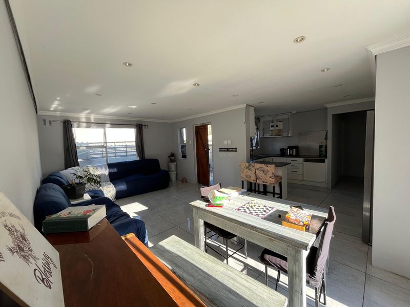 Open-plan living and dining area featuring tiled flooring, recessed lighting, and an integrated kitchen with functional cabinetry and island workspace.