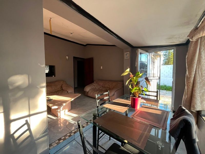 Open plan living and dining area featuring tiled flooring and direct access to the exterior through a security gate.