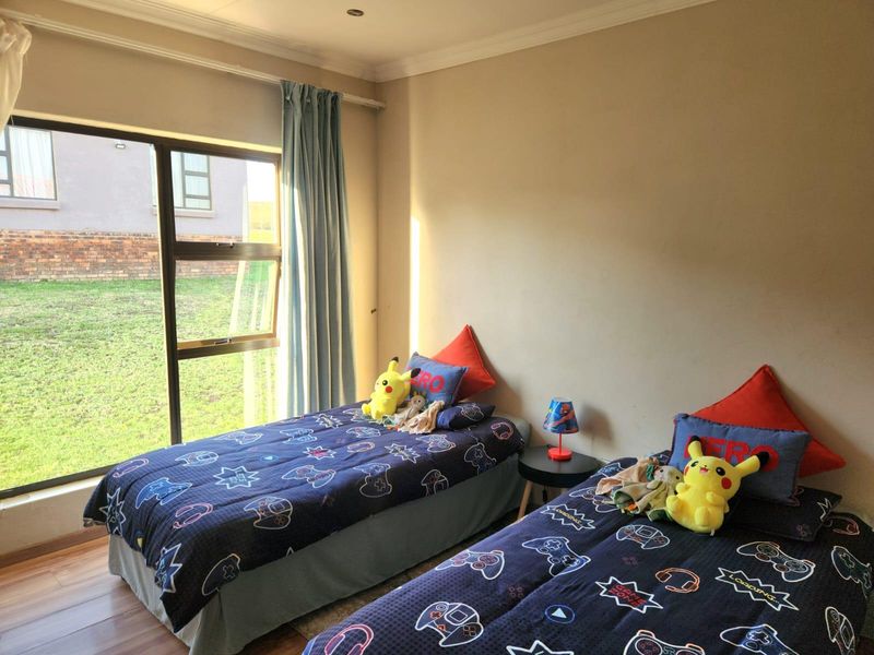 A bedroom featuring laminate flooring, recessed lighting, and a large window providing natural light and views of the garden.