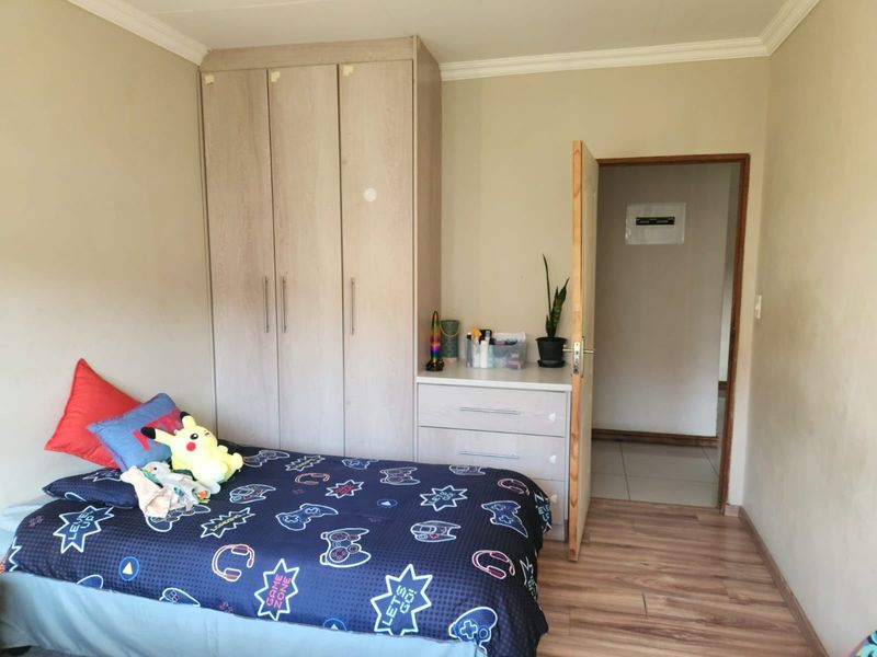 A bedroom featuring light-toned built-in wardrobes with integrated drawer storage and durable laminate flooring.
