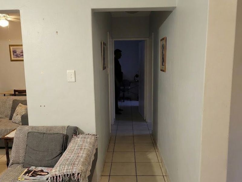 A view from the living area into a tiled hallway leading to other rooms, showing signs of wear on the walls.