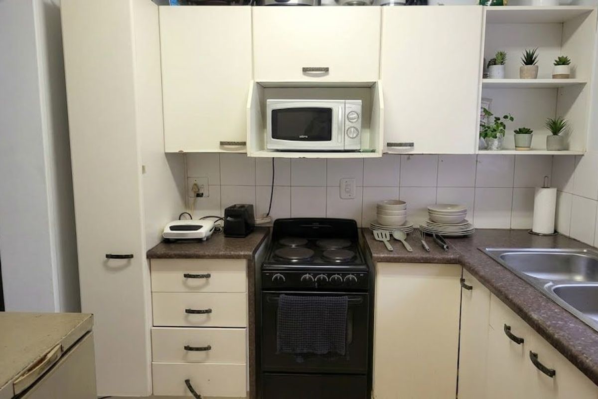 A functional kitchen featuring built-in cabinetry, laminate countertops, a double bowl stainless steel sink, and an electric stove with a built-in microwave.