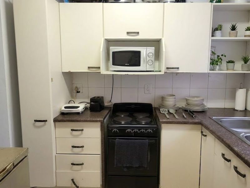 A functional kitchen featuring built-in cabinetry, laminate countertops, a double bowl stainless steel sink, and an electric stove with a built-in microwave.