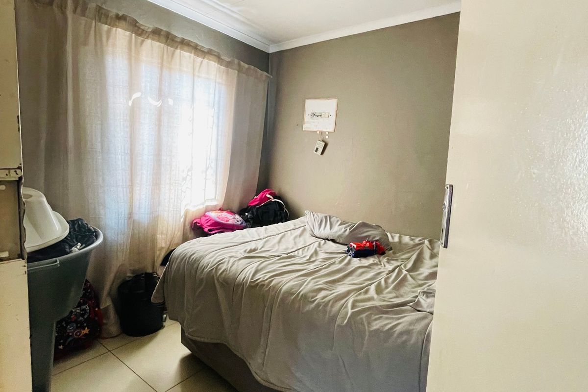 A standard bedroom featuring tiled flooring and coved ceiling details, providing a functional space with natural light from the window.