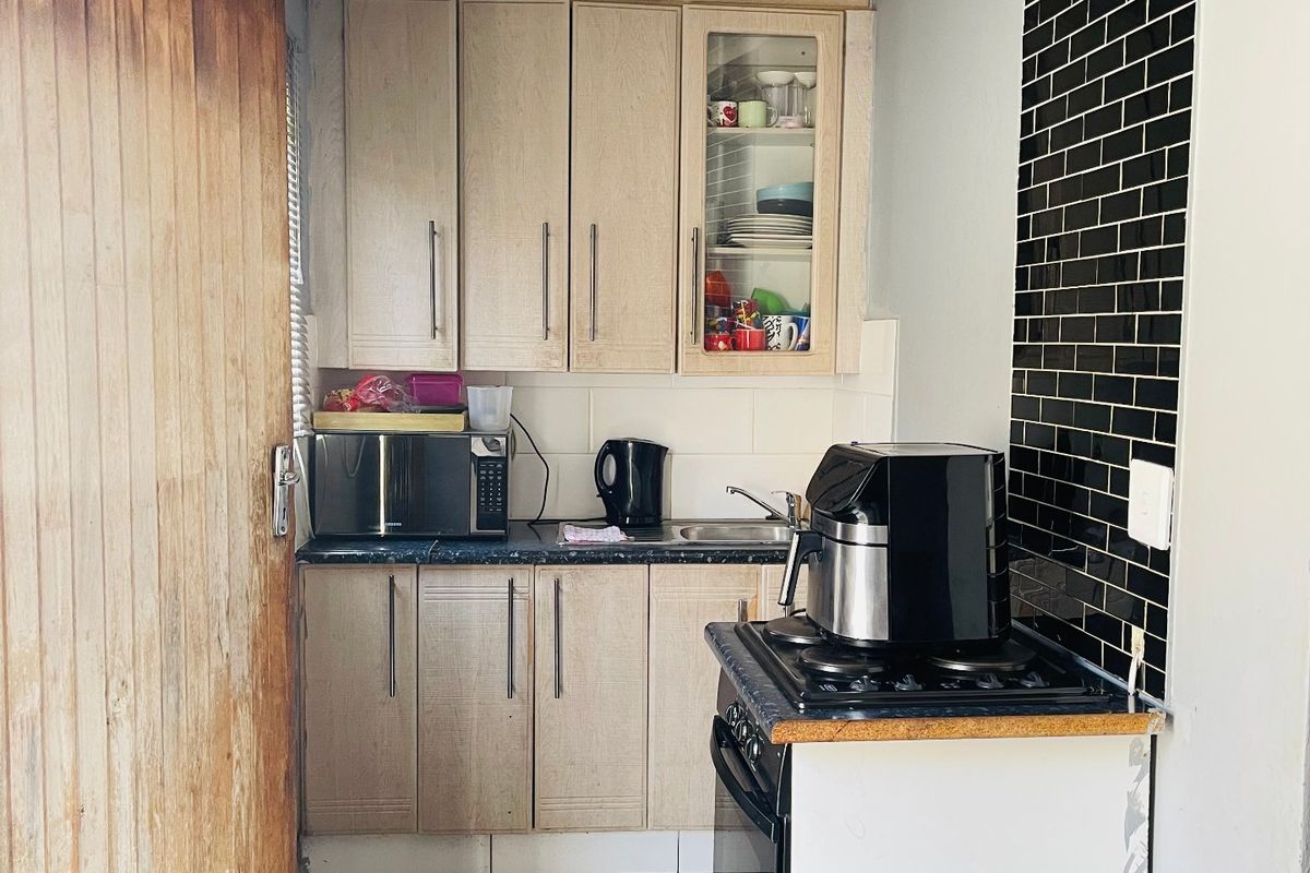 Compact kitchen featuring light wood cabinetry, black subway tile backsplash, gas stove, and tiled flooring, requiring minor finishing touches to complete the space.