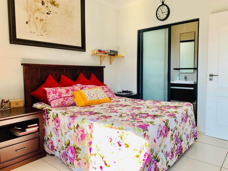 A well-maintained bedroom featuring tiled flooring and an en-suite bathroom accessible via a sliding glass door.