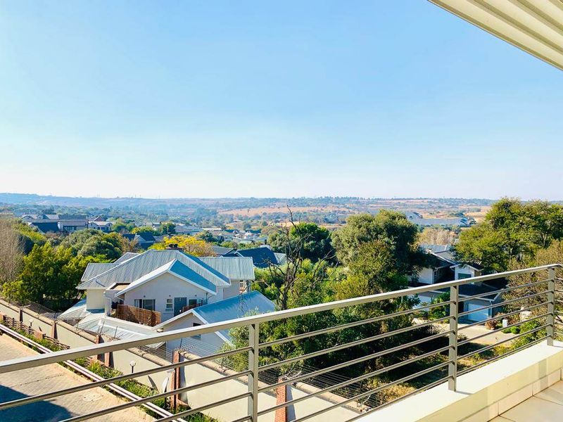 An elevated view from a balcony overlooking a residential neighborhood and surrounding landscape.