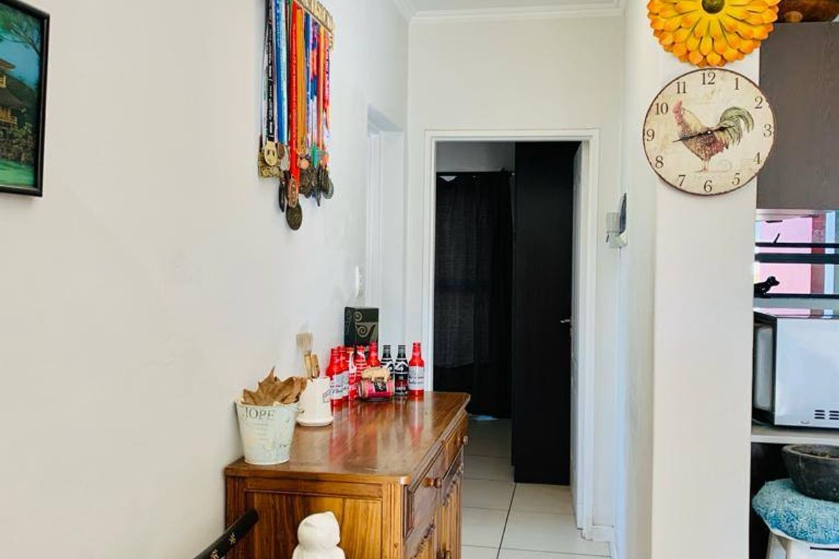A functional hallway featuring tiled flooring and a central ceiling light, providing access to adjacent rooms within the apartment.