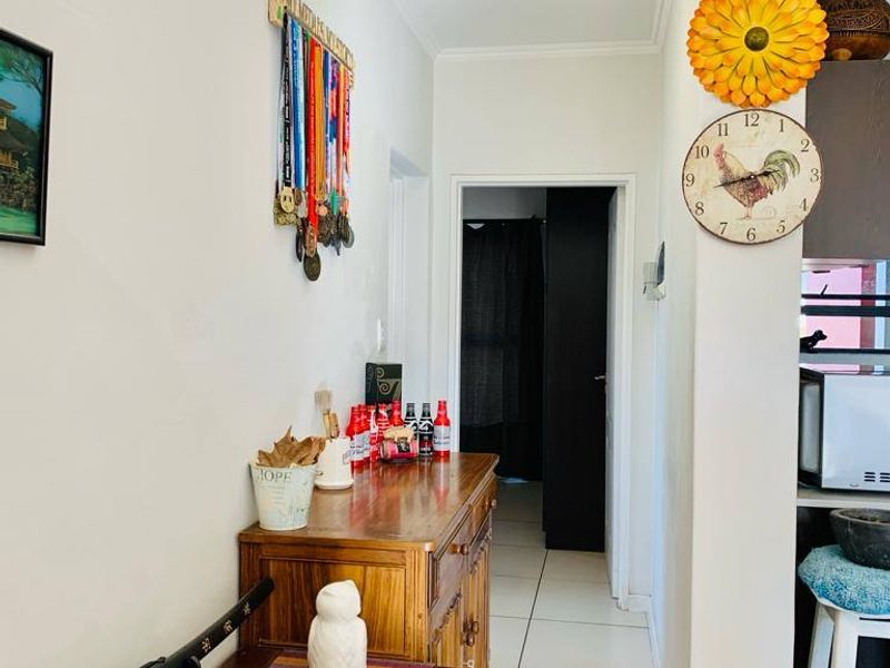 A functional hallway featuring tiled flooring and a central ceiling light, providing access to adjacent rooms within the apartment.