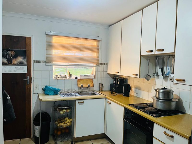 A functional kitchen featuring white built-in cabinetry, laminate countertops, a built-in oven with electric hob, and tiled backsplash.