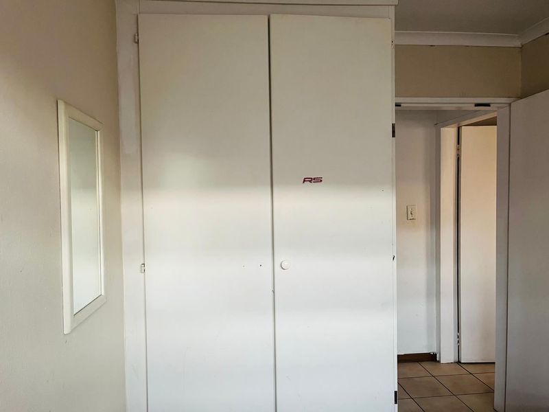 A bedroom featuring built-in cupboards and tiled flooring, requiring minor cosmetic updates to refresh the space.