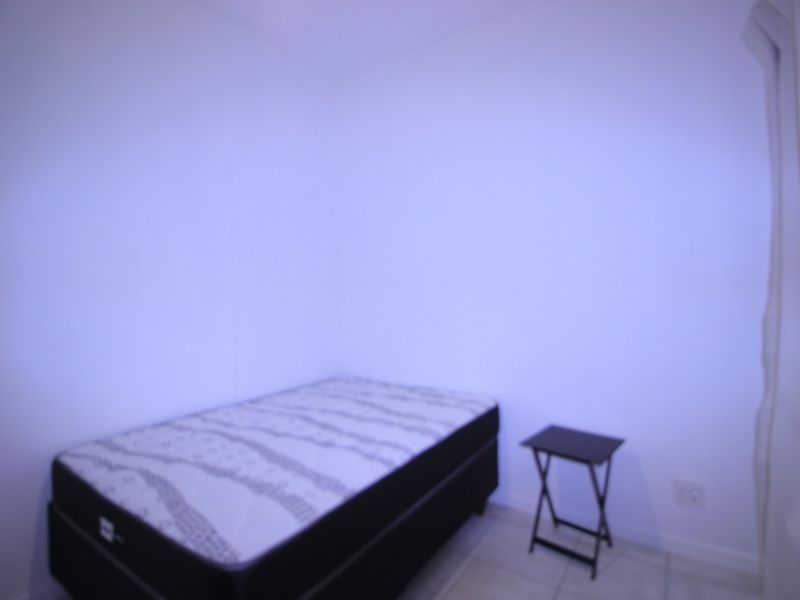 A simple bedroom featuring tiled flooring and neutral walls, providing a blank canvas for personalization.