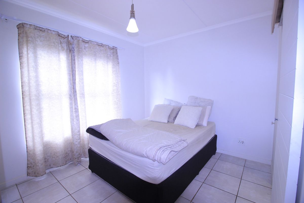 A simple bedroom featuring tiled flooring and a neutral color palette, providing a clean and functional space.