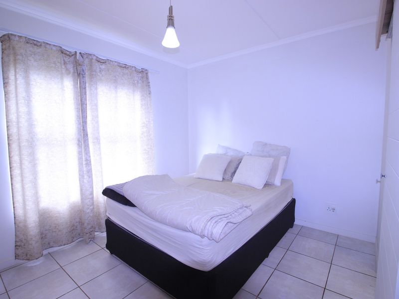A simple bedroom featuring tiled flooring and a neutral color palette, providing a clean and functional space.