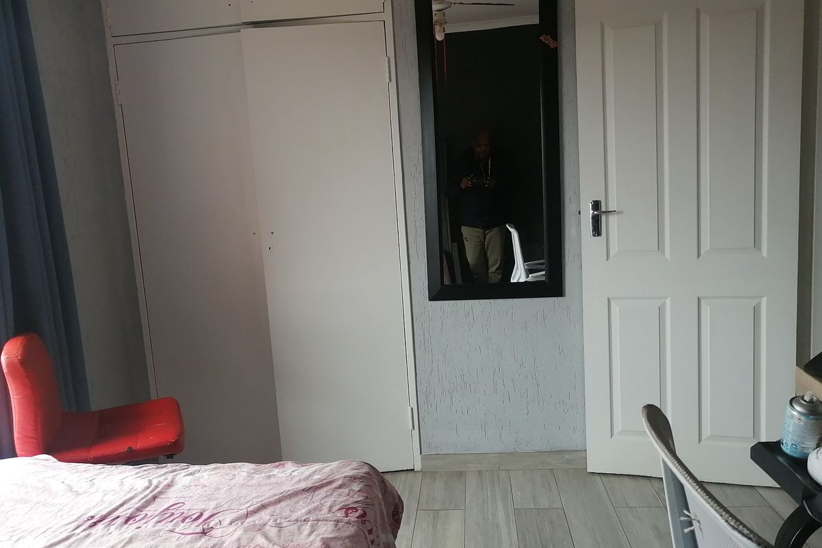 A bedroom featuring built-in cupboards, tiled flooring, and a standard internal door.
