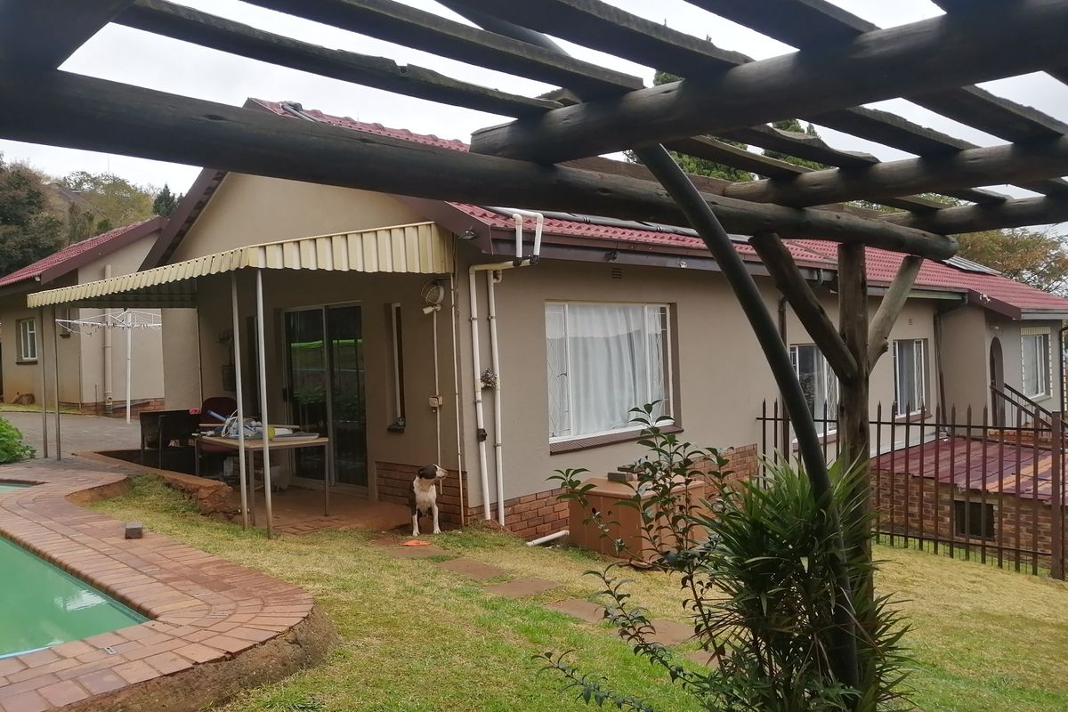 Rear view of the house featuring a swimming pool, brick paved patio area, and a timber pergola structure.