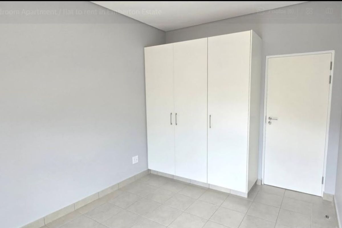 A clean, neutral bedroom featuring built-in cupboards, tiled flooring, and a simple, modern finish.